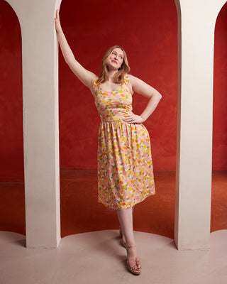 Woman in a floral dress posing against a red wall with arches. This dress is the Irving Dress sewing pattern from Cashmerette.