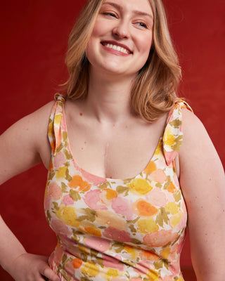 Woman wearing a floral dress against a red background. This dress is the Irving Dress sewing pattern from Cashmerette.