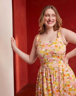 Woman wearing a floral dress against a red wall. This dress is the Irving Dress sewing pattern from Cashmerette.