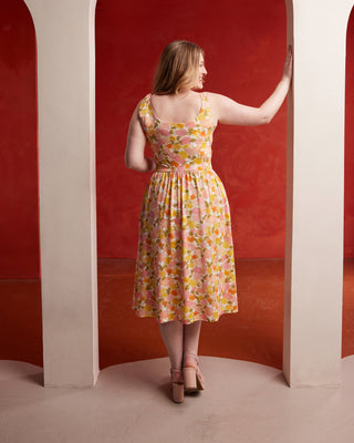 Woman in a floral dress standing in a red archway. This dress is the Irving Dress sewing pattern from Cashmerette.