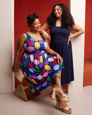 Two women posing together against a red and white striped wall. This dress is the Irving Dress sewing pattern from Cashmerette.
