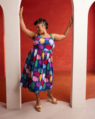 Woman wearing a colorful dress standing in a red and white archway. This dress is the Irving Dress sewing pattern from Cashmerette.