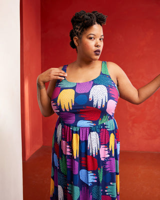 Woman wearing a colorful dress with abstract patterns against a red background. This dress is the Irving Dress sewing pattern from Cashmerette.