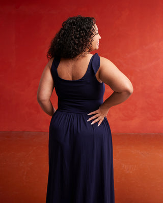 Woman wearing a navy blue dress against a red background. This dress is the Irving Dress sewing pattern from Cashmerette.