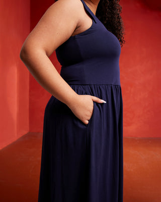 Person wearing a navy blue dress against a red background. This dress is the Irving Dress sewing pattern from Cashmerette.