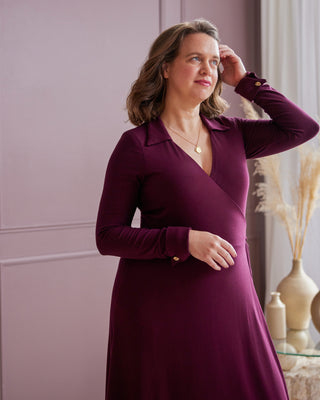 Woman wearing a purple dress indoors with a neutral background. This is the Hazelton Wrap Dress sewing pattern from Cashmerette.