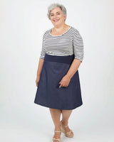 Woman wearing a striped shirt and navy skirt on a white background. This dress is the Washington Dress sewing pattern from Cashmerette.