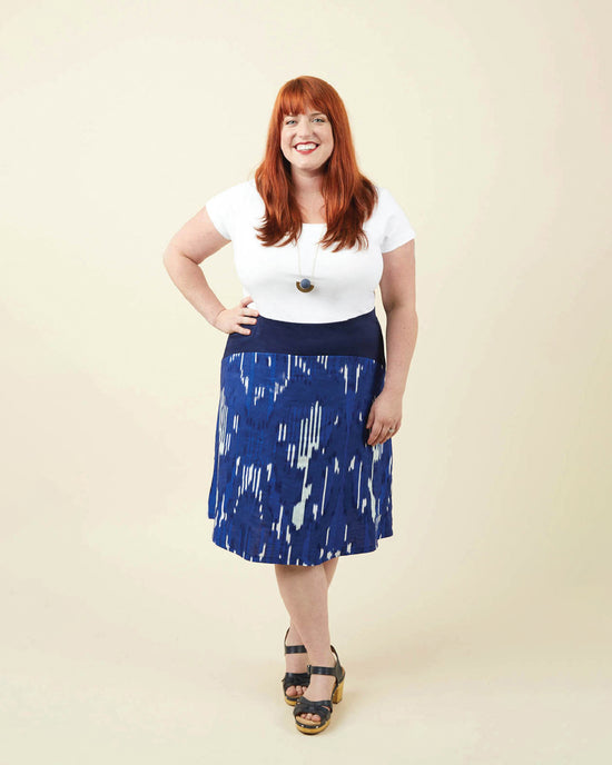 Woman wearing a white top and blue patterned skirt against a beige background. This dress is the Washington Dress sewing pattern from Cashmerette.
