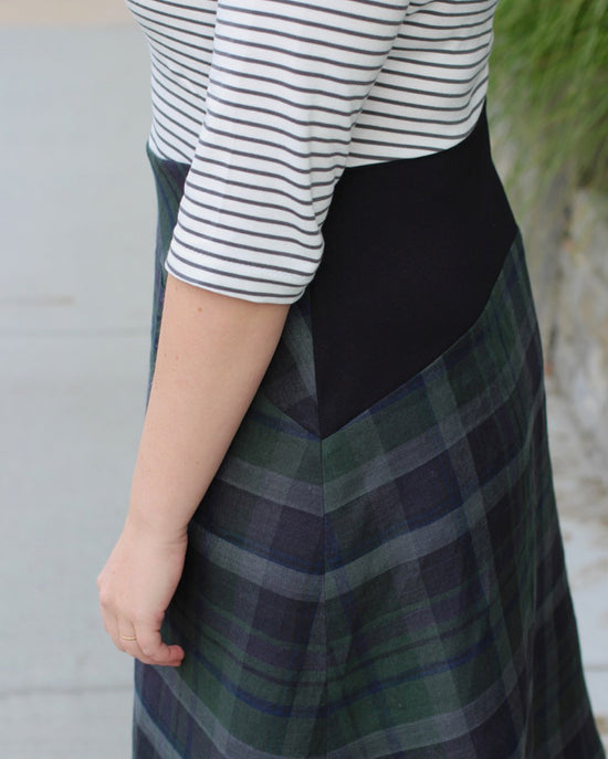 Person wearing a striped shirt and plaid skirt with a blurred background. This dress is the Washington Dress sewing pattern from Cashmerette.