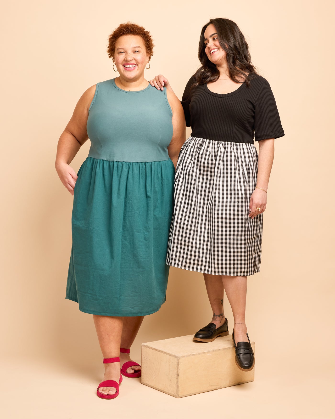 Two women wearing dresses standing on a beige background. This is the Duxbury Dress sewing pattern from Cashmerette