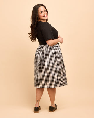 Woman wearing a black and white checkered skirt against a beige background. This is the Duxbury Dress sewing pattern from Cashmerette.