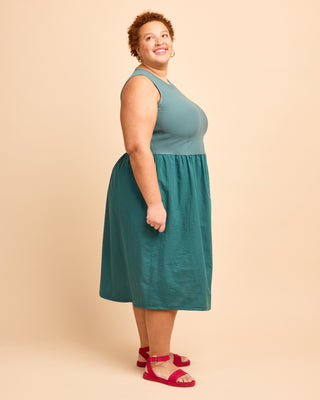 Woman wearing a teal dress on a beige background. This is the Duxbury Dress sewing pattern from Cashmerette.
