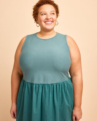 Woman wearing a teal dress against a beige background. This is the Duxbury Dress sewing pattern from Cashmerette.