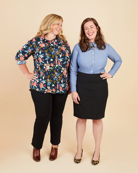 Two women standing side by side against a beige background, wearing colorful shirts and black pants.. This button-up shirt is the Harrison Shirt sewing pattern from Cashmerette.