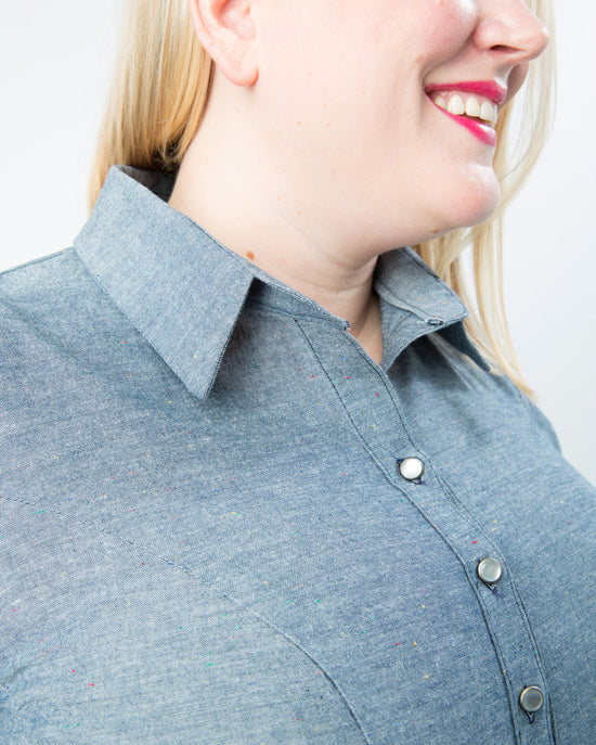 Person wearing a blue shirt with a collar against a plain background. This button-up shirt is the Harrison Shirt sewing pattern from Cashmerette.