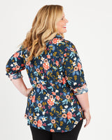 Woman wearing a navy floral blouse on a white background. This button-up shirt is the Harrison Shirt sewing pattern from Cashmerette.