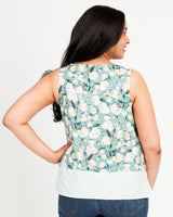 Woman wearing a sleeveless floral top with a light blue background. This top is the Springfield Top sewing pattern from Cashmerette.