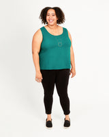 Woman wearing a green sleeveless top and black pants on a white background. This top is the Springfield Top sewing pattern from Cashmerette.
