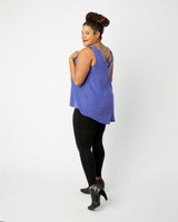 Woman wearing a blue sleeveless top and black leggings on a white background. This top is the Webster Dress & Tunic sewing pattern from Cashmerette.