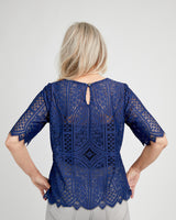 Woman wearing a blue lace top with a plain background. This top is the Montrose Top sewing pattern from Cashmerette.