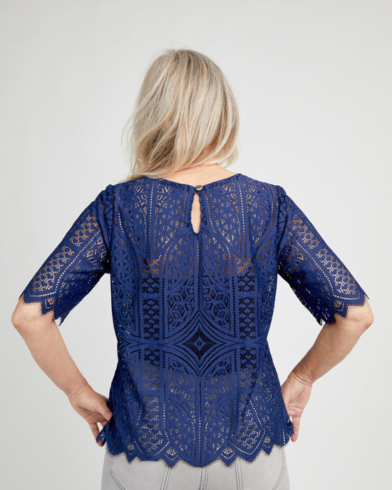 Woman wearing a blue lace top with a plain background. This top is the Montrose Top sewing pattern from Cashmerette.