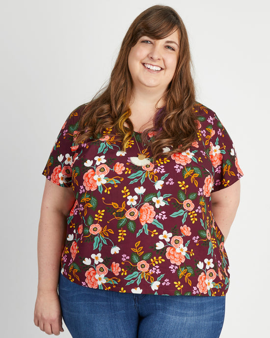 Woman wearing a floral blouse with a plain background. This top is the Montrose Top sewing pattern from Cashmerette.