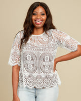 Woman wearing a white lace top against a beige background. This top is the Montrose Top sewing pattern from Cashmerette.