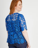 Woman wearing a blue lace top against a plain background. This top is the Montrose Top sewing pattern from Cashmerette.