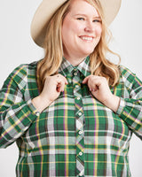 Person wearing a green plaid shirt with a beige hat on a white background. This top is the Vernon Shirt sewing pattern from Cashmerette.