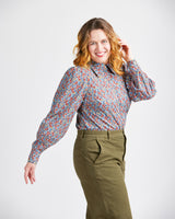 Woman wearing a patterned blouse and green pants on a white background. This top is the Vernon Shirt sewing pattern from Cashmerette.