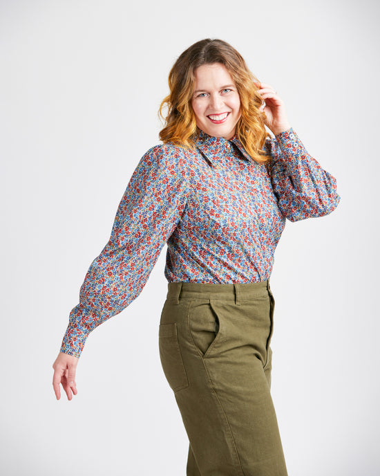Woman wearing a patterned blouse and green pants on a white background. This top is the Vernon Shirt sewing pattern from Cashmerette.