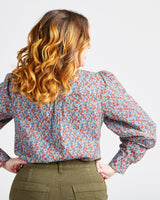 Woman wearing a floral blouse with long sleeves on a plain background. This top is the Vernon Shirt sewing pattern from Cashmerette.