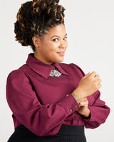 Woman wearing a burgundy shirt with a white background. This top is the Vernon Shirt sewing pattern from Cashmerette.