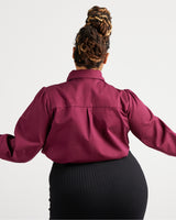 Person wearing a burgundy shirt with long sleeves on a white background. This top is the Vernon Shirt sewing pattern from Cashmerette.