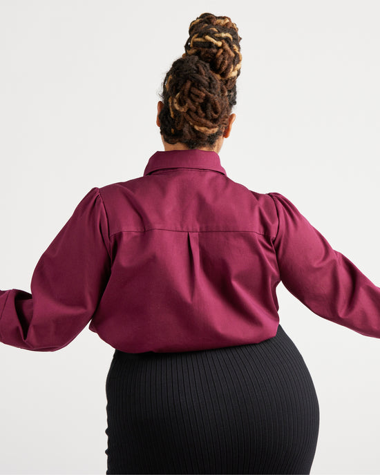 Person wearing a burgundy shirt with long sleeves on a white background. This top is the Vernon Shirt sewing pattern from Cashmerette.