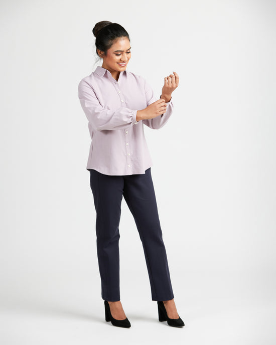 Woman wearing a light pink blouse and dark pants on a white background. This top is the Vernon Shirt sewing pattern from Cashmerette.