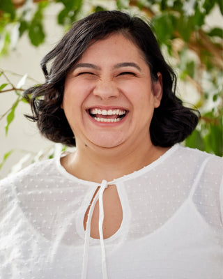Person wearing a white blouse with a blurred natural background. This top is the Alton Blouse sewing pattern from Cashmerette.