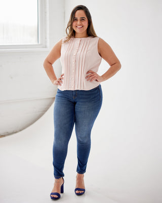 Woman wearing a sleeveless top and blue jeans standing in a bright room. This top is the Selwyn Top sewing pattern from Cashmerette.