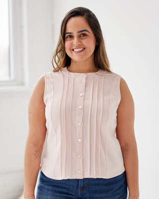 Woman wearing a light pink blouse with buttons and blue jeans indoors. This top is the Selwyn Top sewing pattern from Cashmerette.