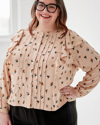 Woman wearing a beige blouse with a floral pattern against a white background. This top is the Selwyn Top sewing pattern from Cashmerette.