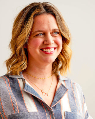 Woman with wavy blonde hair wearing a striped shirt against a plain background. Woman wearing a plaid shirt and denim shorts against a neutral background. This top is the Haskell Shirt sewing pattern from Cashmerette.