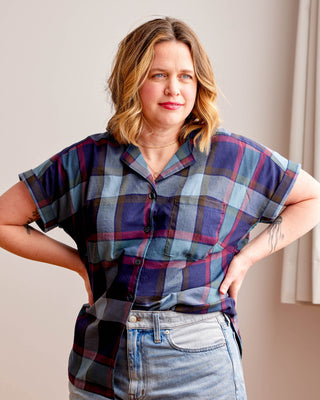 Woman wearing a plaid shirt and jeans against a neutral background. Woman wearing a plaid shirt and denim shorts against a neutral background. This top is the Haskell Shirt sewing pattern from Cashmerette.