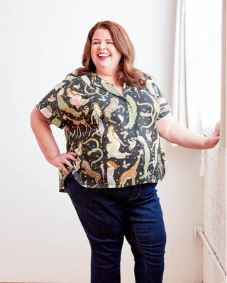 Woman wearing a patterned shirt and jeans indoors. Woman wearing a plaid shirt and denim shorts against a neutral background. This top is the Haskell Shirt sewing pattern from Cashmerette.
