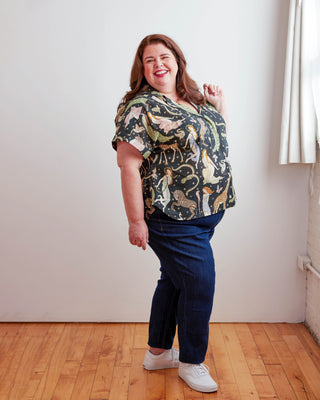 Woman wearing a patterned shirt and blue pants standing in a room with wooden floor and white walls. Woman wearing a plaid shirt and denim shorts against a neutral background. This top is the Haskell Shirt sewing pattern from Cashmerette.