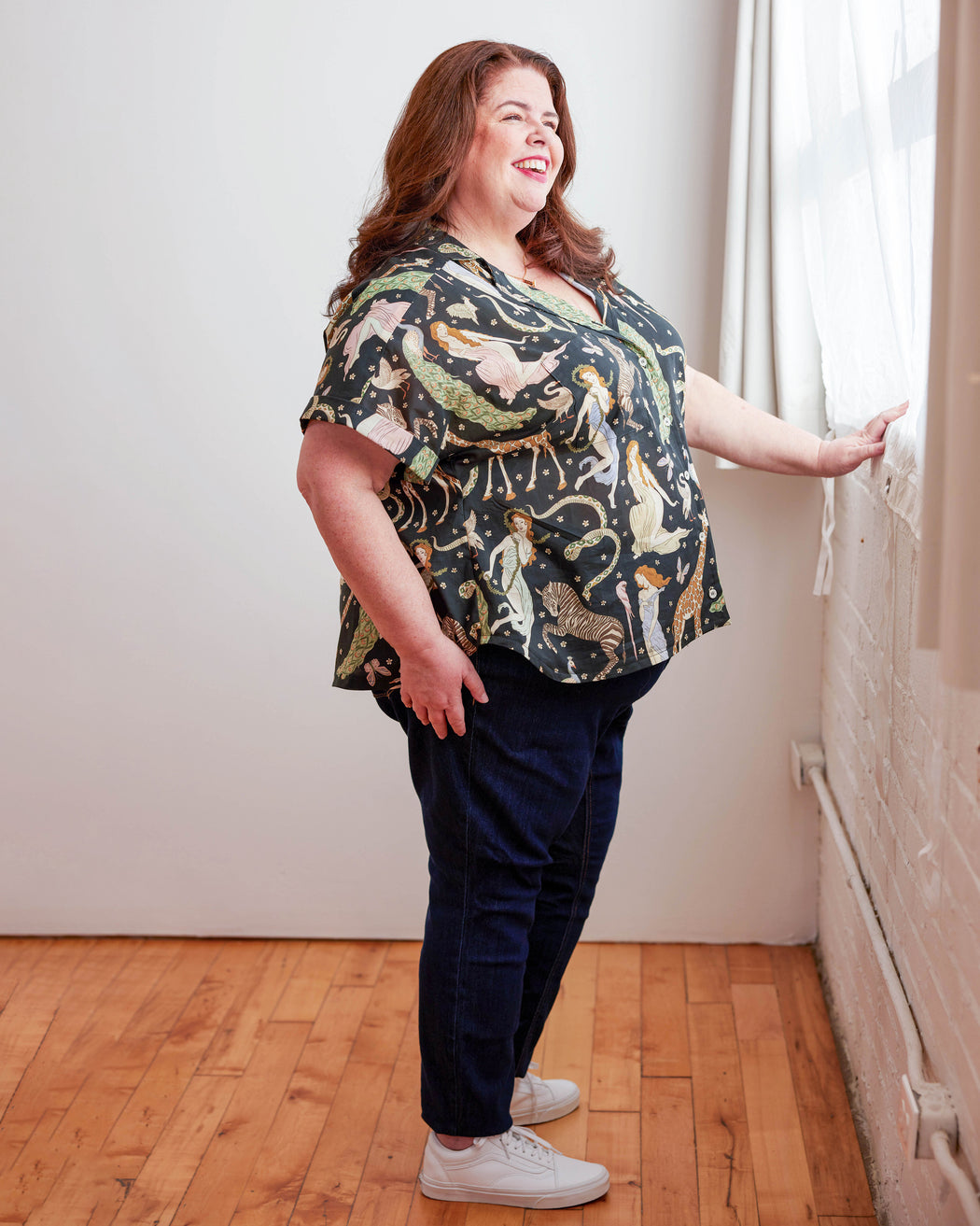 Woman wearing a patterned top and dark pants standing in a room with wooden flooring and white walls. Woman wearing a plaid shirt and denim shorts against a neutral background. This top is the Haskell Shirt sewing pattern from Cashmerette.