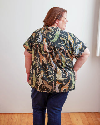 Person wearing a patterned shirt with animals on a plain background. Woman wearing a plaid shirt and denim shorts against a neutral background. This top is the Haskell Shirt sewing pattern from Cashmerette.