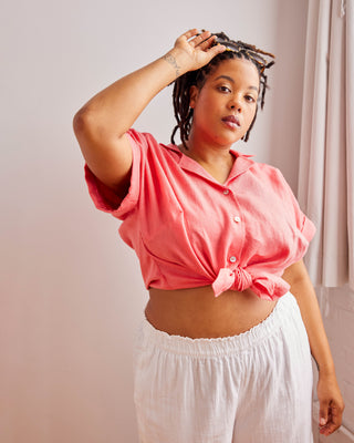 Woman wearing a pink top and white pants against a plain background. Woman wearing a plaid shirt and denim shorts against a neutral background. This top is the Haskell Shirt sewing pattern from Cashmerette.