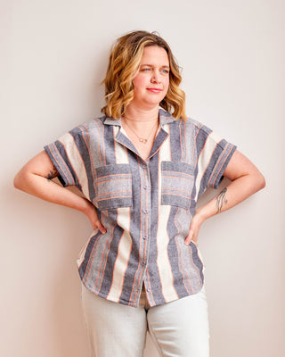 Woman wearing a striped shirt against a plain background. Woman wearing a plaid shirt and denim shorts against a neutral background. This top is the Haskell Shirt sewing pattern from Cashmerette.