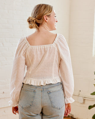 Woman wearing a light blouse with a subtle pattern and high-waisted jeans indoors. This top is the Briarwood Top sewing pattern from Cashmerette.