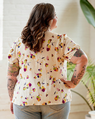 Person wearing a floral blouse with a blurred indoor background. This top is the Swanton Pussy Bow Blouse sewing pattern from Cashmerette.